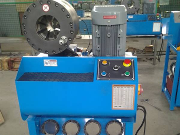 A blue high pressure hose crimping machine (type H) controlled by buttons is on the ground.
